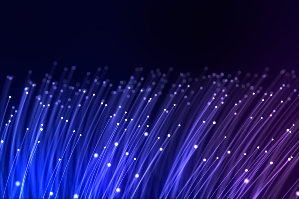 Image of glowing fiber optic cables with white lights against a dark blue-purple gradient background. ioPro.com tld domain is for sale.